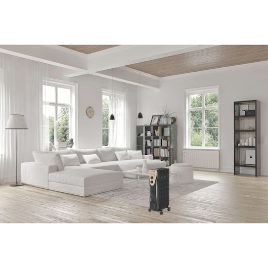 BLACKDECKER OR070D portable radiator heater in living room setting with light wood floors and white furniture.