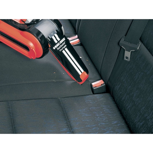 Photo of BLACK+DECKER PAV1205 handheld vacuum cleaning car seat fabric, nozzle reaching seat crevice.
