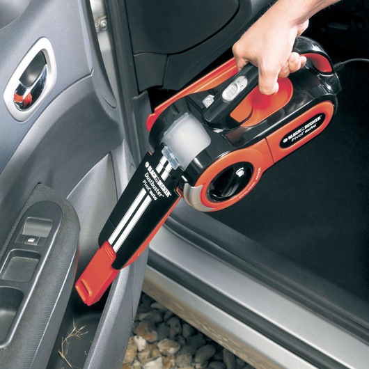 BLACK+DECKER PAV1205 handheld vacuum cleaner in black and orange cleaning a car interior.