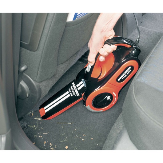BLACK+DECKER PAV1205 handheld car vacuum in black and red used to clean car floor.