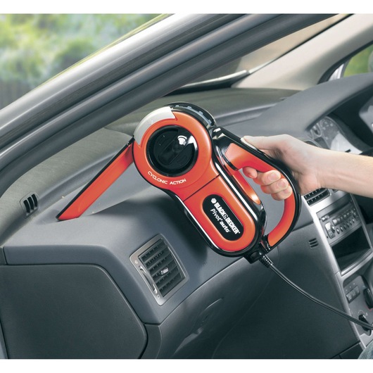 Photo of BLACKDECKER PAV1205 handheld car vacuum cleaner in use, cleaning dashboard with red nozzle.