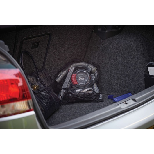 BLACK+DECKER PD1200AV portable car vacuum in car trunk, gray and red, with bag and accessories visible.