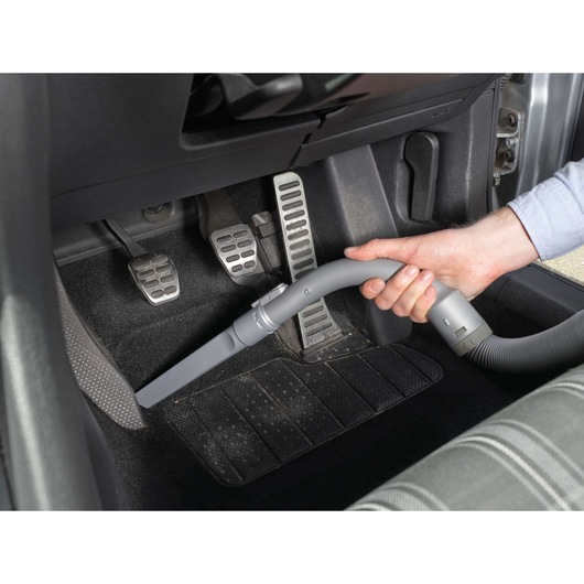 BLACKDECKER PD1200AV car vacuum cleaning footwell area with narrow nozzle attachment, close-up view.