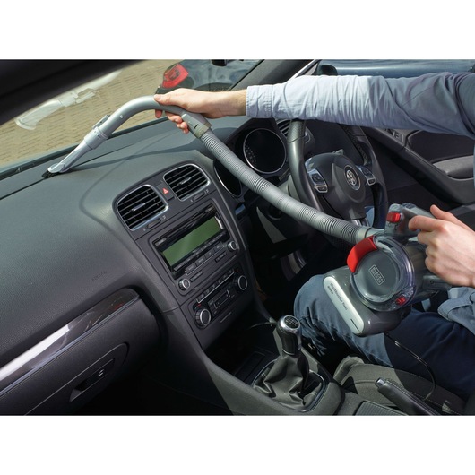 Photo of BLACK+DECKER PD1200AV portable car vacuum being used on a car dashboard with flexible hose attachment.