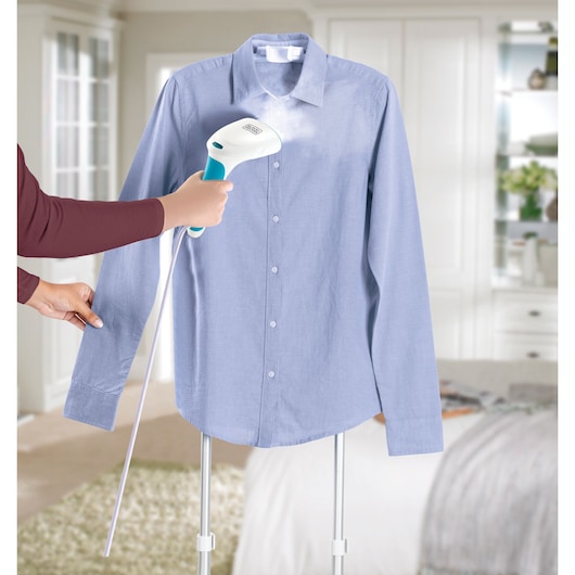 BLACKDECKER PGST120 handheld garment steamer used on light blue shirt in home setting.