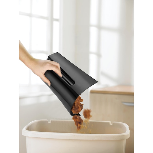 BLACKDECKER PRJE700 black dustbin accessory with handle releasing debris into a waste bin, side angle.