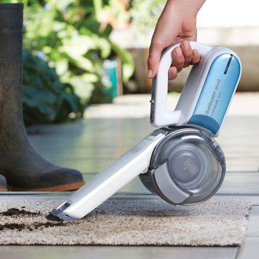 Photo of BLACKDECKER PV1020L handheld vacuum cleaning dirt from a rug, blue and white body.