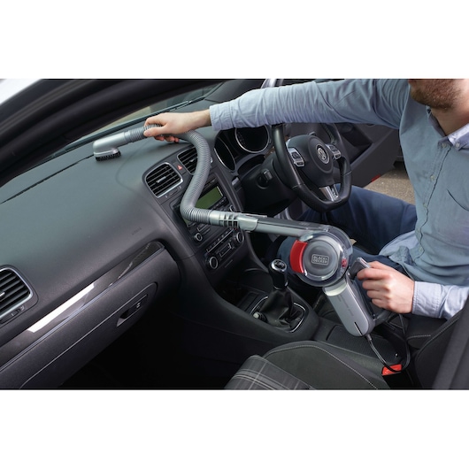BLACK+DECKER PV1200AV handheld car vacuum with flexible hose cleaning a car dashboard.