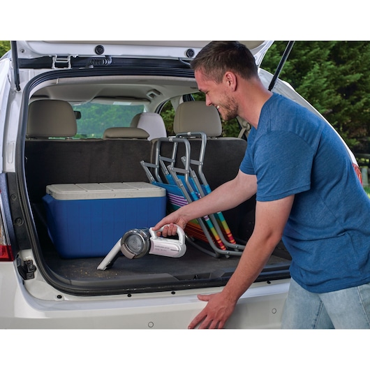 BLACKDECKER PV1820LRGP handheld vacuum cleaning car trunk near cooler and folding chairs.