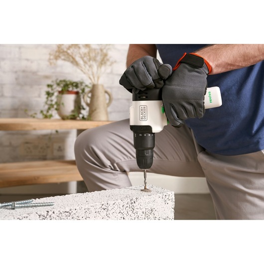 Photo of BLACKDECKER REVHD12C cordless drill in use with gloved hands drilling into concrete indoors.
