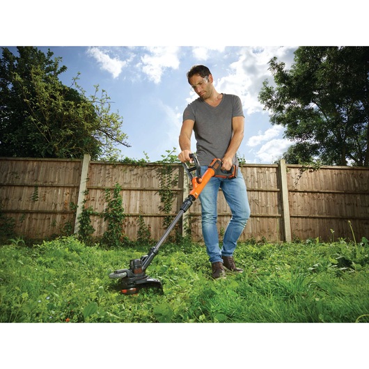 Photo of BLACKDECKER STC1820PCB grass trimmer being used in a garden.