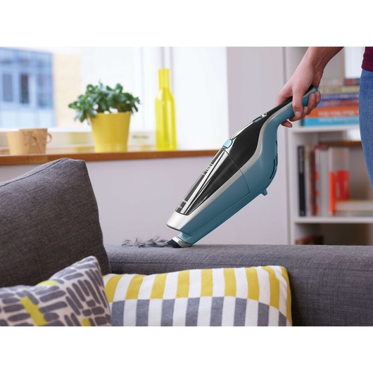 BLACKDECKER SVA420B handheld vacuum cleaning a gray sofa in a modern living room setting.