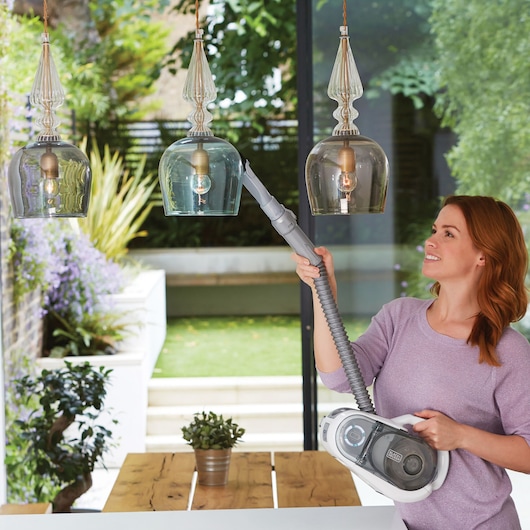 BLACKDECKER SVFV3250L handheld vacuum with extension hose cleaning glass pendant lights indoors.