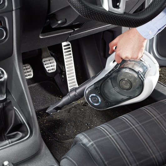 BLACKDECKER SVFV3250L handheld vacuum cleaning car interior floor near pedals.