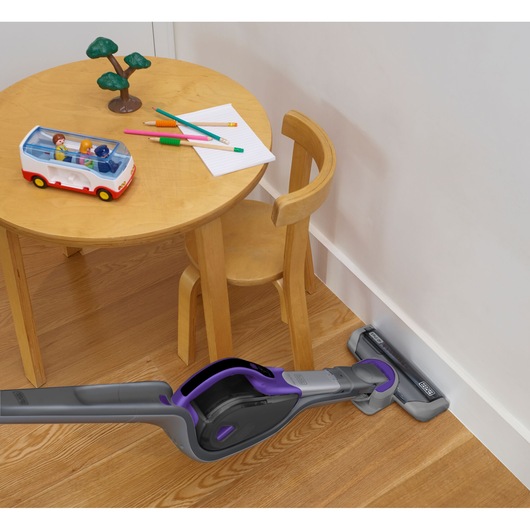 BLACKDECKER SVJ520BFSP cordless vacuum in grey and purple cleaning corner near wooden kids table and chair
