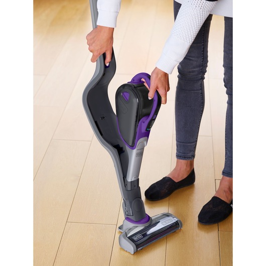 BLACKDECKER SVJ520BFSP cordless stick vacuum in gray and purple, handheld unit being detached, indoor setting