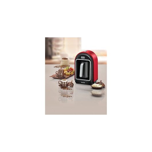 BLACKDECKER TCM700 red Turkish coffee machine on a table with cups, sweets, and coffee beans.