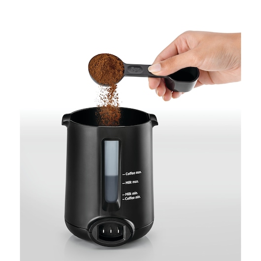 Photo of BLACKDECKER TCM730 coffee maker container with transparent window, being filled with ground coffee using a scoop, front angle.