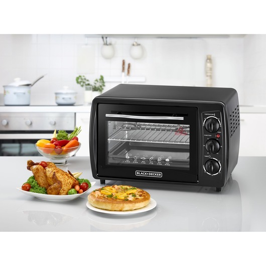 BLACK+DECKER TRO19RDG black countertop oven with glass door, shown in kitchen with food plates.