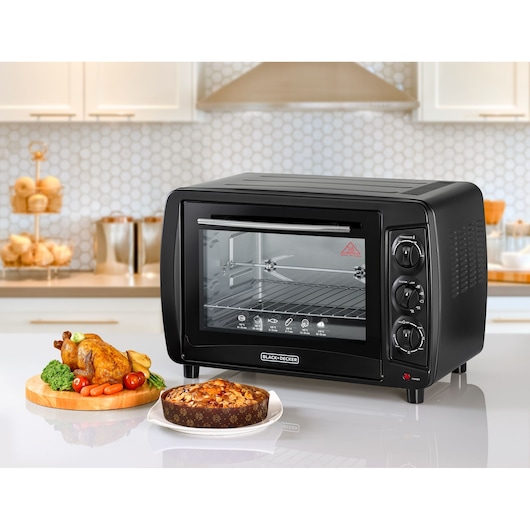 BLACKDECKER TRO35RDG countertop oven, black, front angle, in kitchen with food beside.