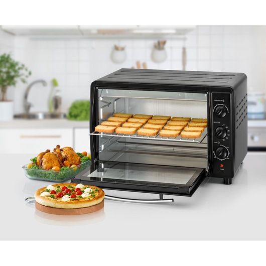 BLACKDECKER TRO45RDG countertop oven with open door, toasted bread slices inside, pizza and roasted chicken nearby.