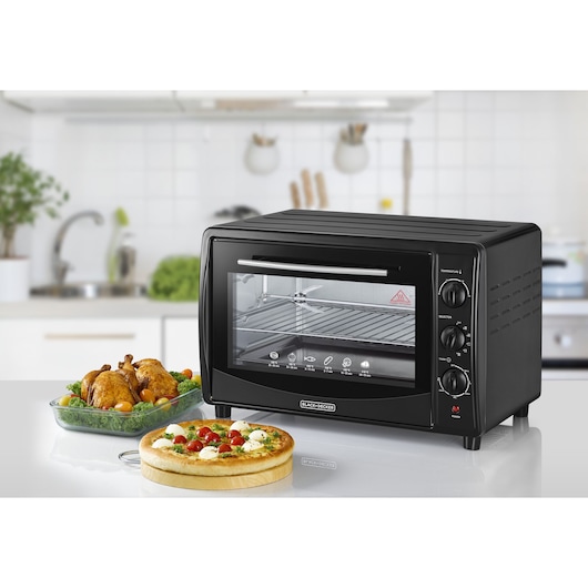 BLACK+DECKER TRO45RDG black countertop oven with glass door, three control knobs, photographed in a modern kitchen.