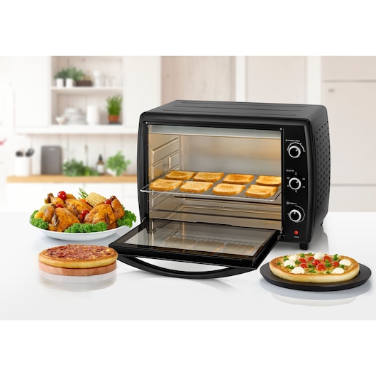 BLACKDECKER TRO70RDG black countertop oven with open door, toasts inside, and assorted food including chicken and pizza in kitchen.