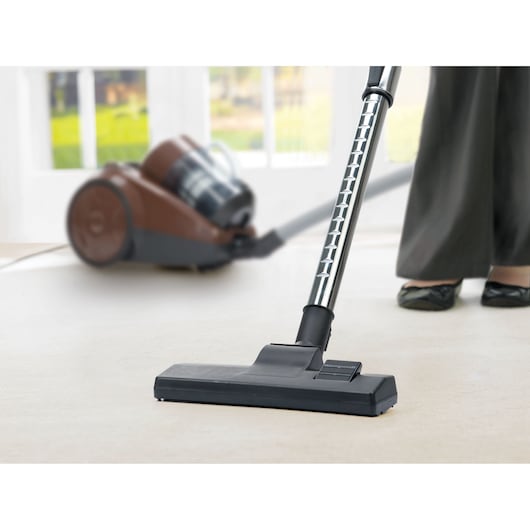 BLACK+DECKER V01850-B5 canister vacuum cleaner on light carpet, close-up of floor nozzle in use.