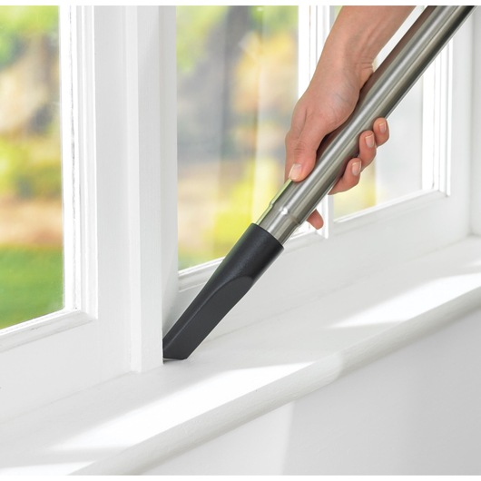 BLACKDECKER VM2825 vacuum cleaner nozzle cleaning window sill in close-up photography.