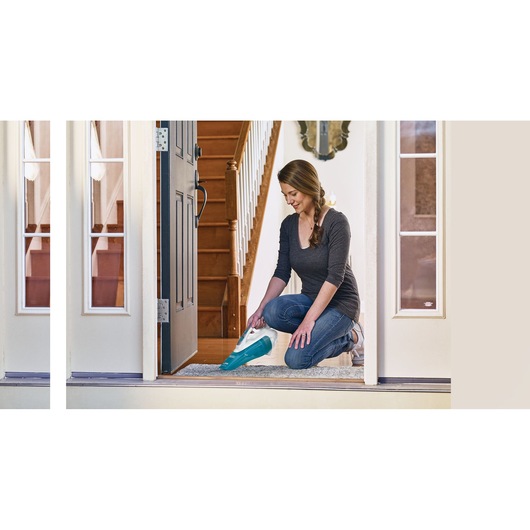 BLACK+DECKER WDA315J handheld vacuum in use cleaning a carpeted entryway inside a home.