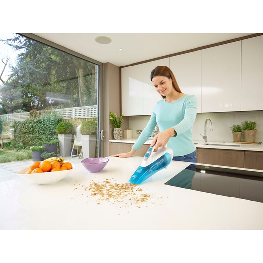 BLACKDECKER WDA315J handheld vacuum cleaning crumbs on a white kitchen counter next to a fruit bowl.