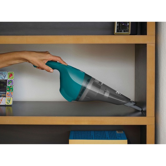 BLACK+DECKER WDB115WA handheld vacuum in teal cleaning shelf edge with crevice tool attachment.