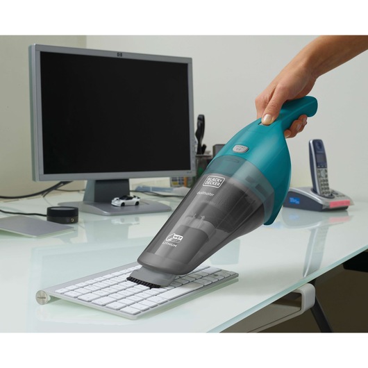 Photo of BLACK+DECKER WDB115WA handheld vacuum cleaning a keyboard on an office desk.