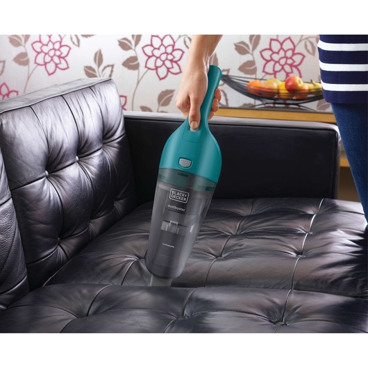 BLACKDECKER WDB115WA handheld vacuum cleaner cleaning black leather sofa indoors.