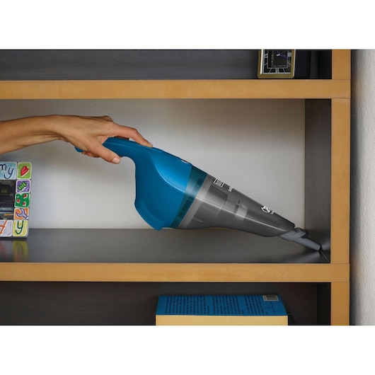 BLACKDECKER WDB215WA handheld vacuum cleaner in blue used to clean a wooden shelf.