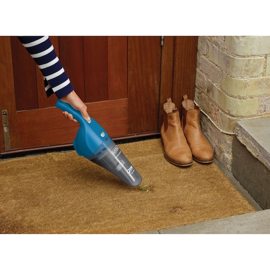 Photo of BLACKDECKER WDB215WA handheld vacuum in blue, cleaning a doormat at an entrance.