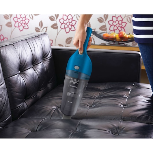 BLACK+DECKER WDB215WA handheld vacuum with blue top cleaning black leather sofa.