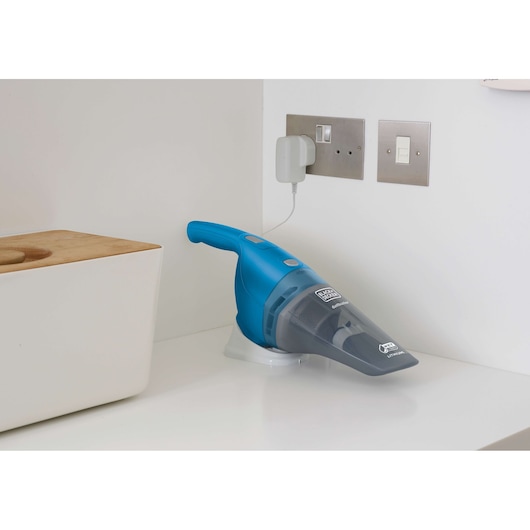 BLACKDECKER WDB215WA handheld vacuum in blue, charging on a white countertop in a kitchen corner.