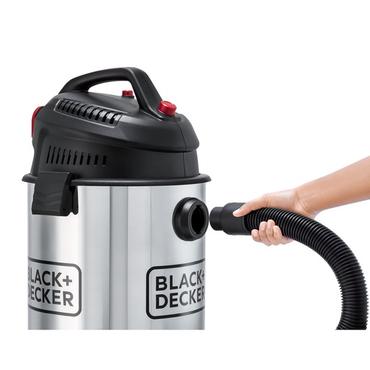 Photo of BLACK+DECKER WV1450 wet/dry vacuum cleaner, stainless steel body, hose being attached, side view, white background.