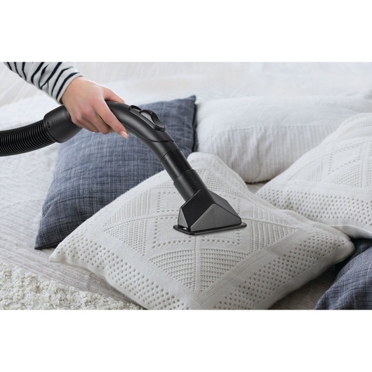 BLACKDECKER WV1450 vacuum cleaner cleaning a textured white pillow on a bed, close-up action view